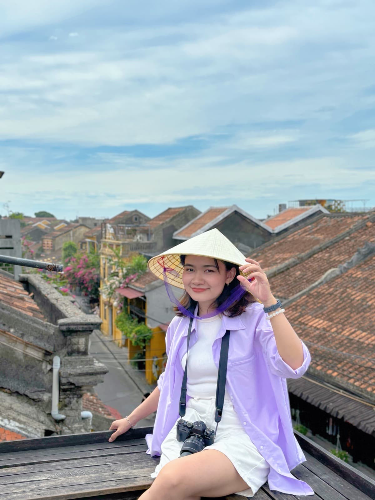 Phuong Le wearing a conical hat on a rooftop overlooking Hoi An's old town